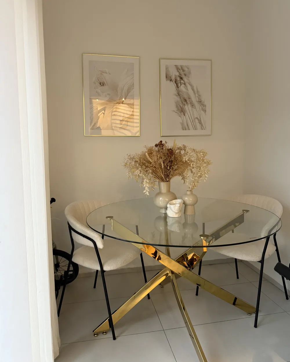 Dining room with a glass table and gold legs, white chairs, and wall art.