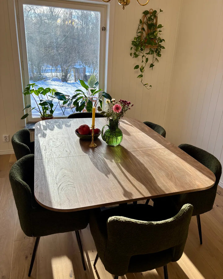Dining area with a wooden table and chairs in a room with a large window.