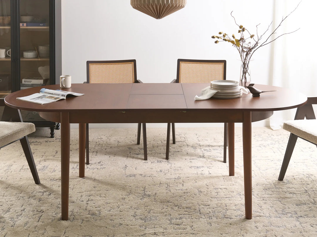 Dining room with a wooden table and chairs, featuring a vase with flowers and plates.
