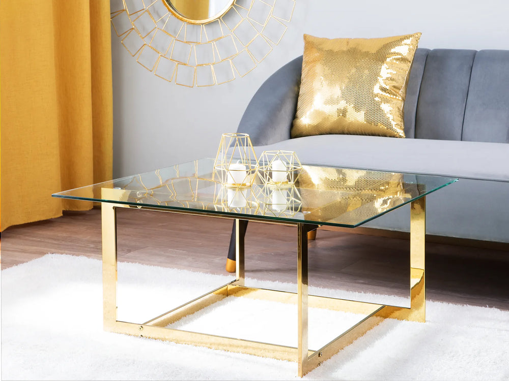 Glass coffee table with gold frame in a living room setting