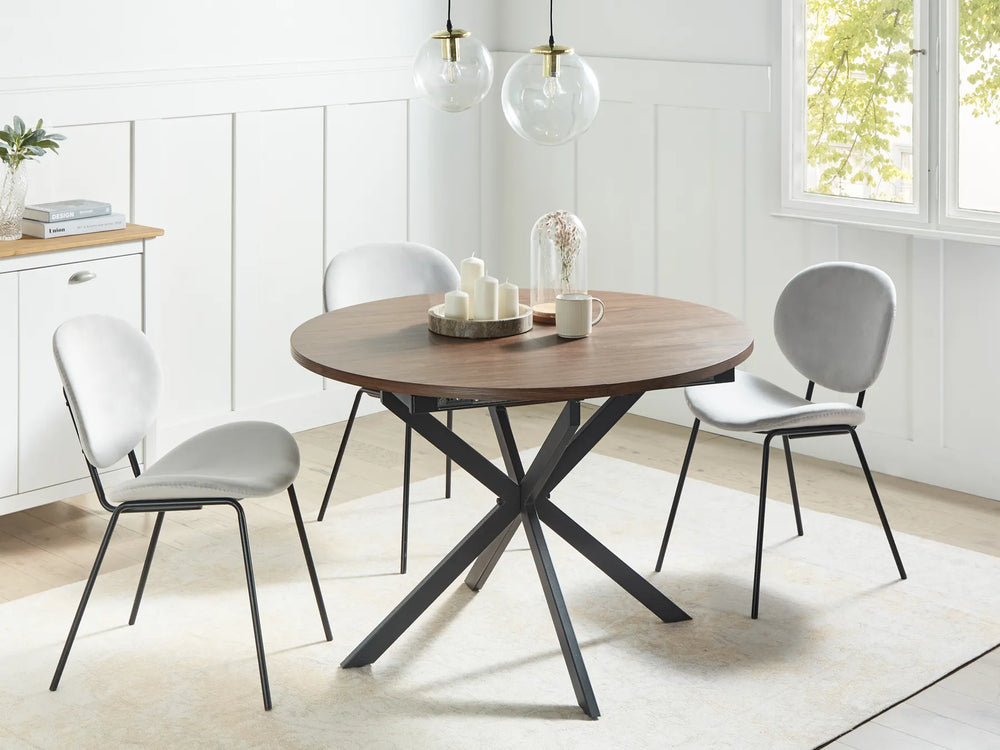 Dining room with a round wooden table and gray chairs in a bright room.