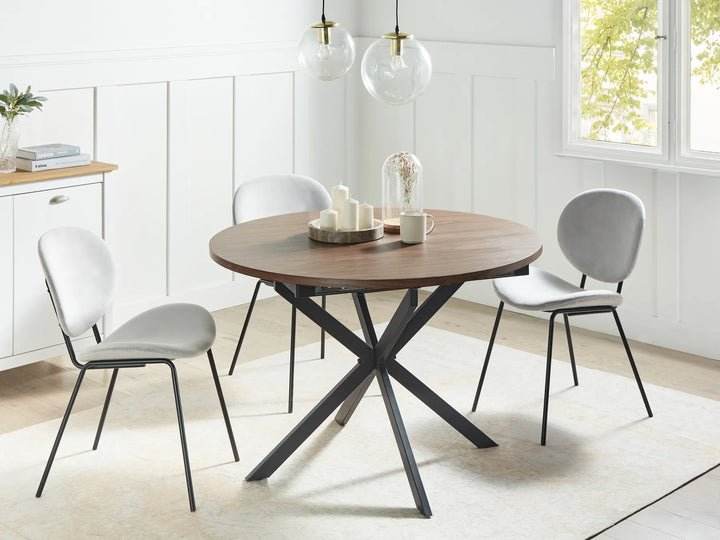 Dining room with a round wooden table and gray chairs in a bright room.