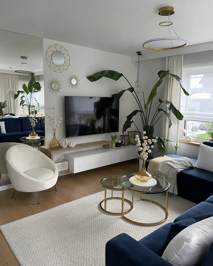 Modern living room with a TV, blue sofa, white armchair, and decorative elements.