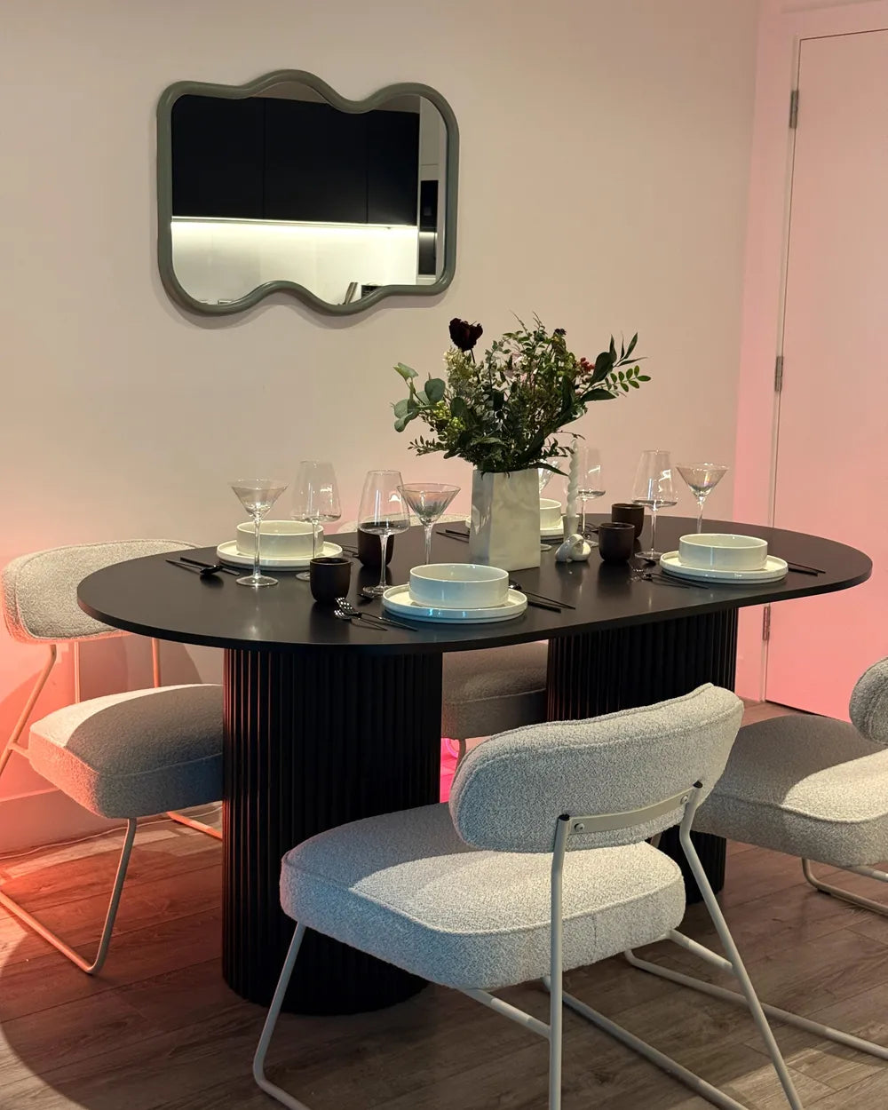 Dining room with a black oval table, white chairs, and decorative items.