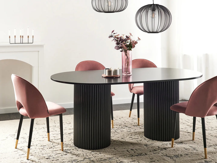 Dining room with a black round table and pink chairs.