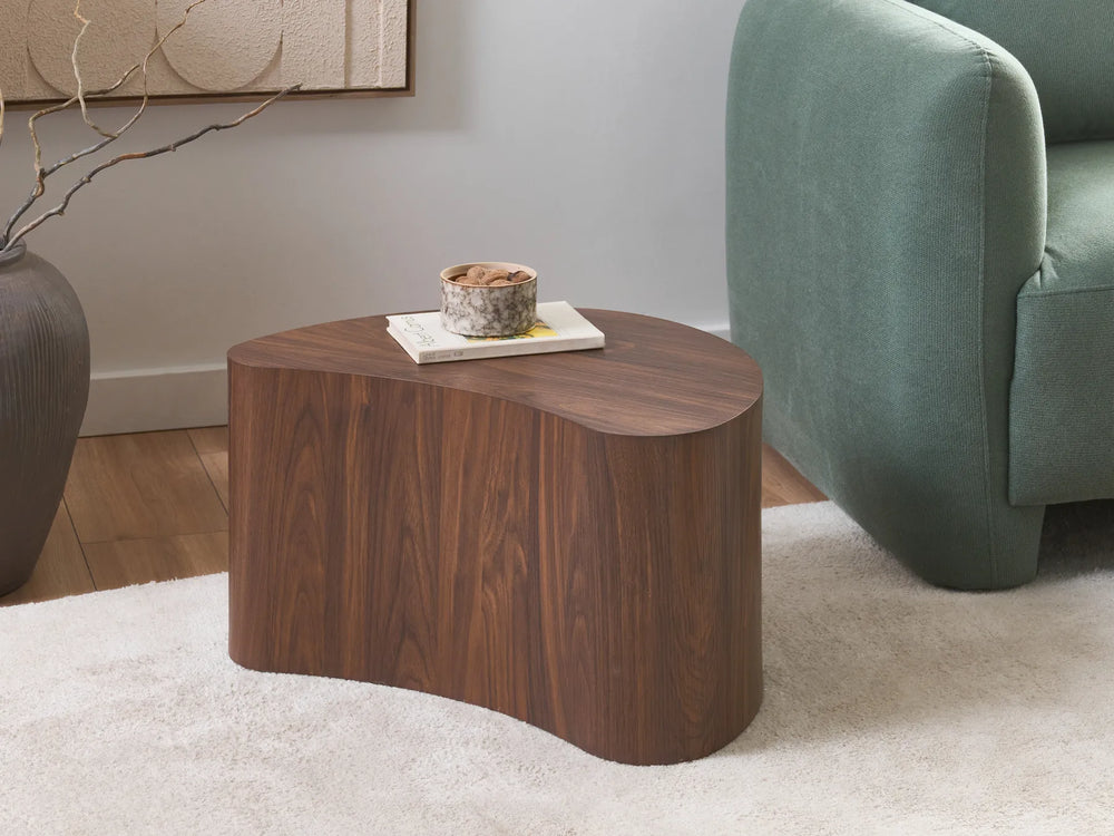 Wooden side table in a living room setting with a green sofa and decorative items.