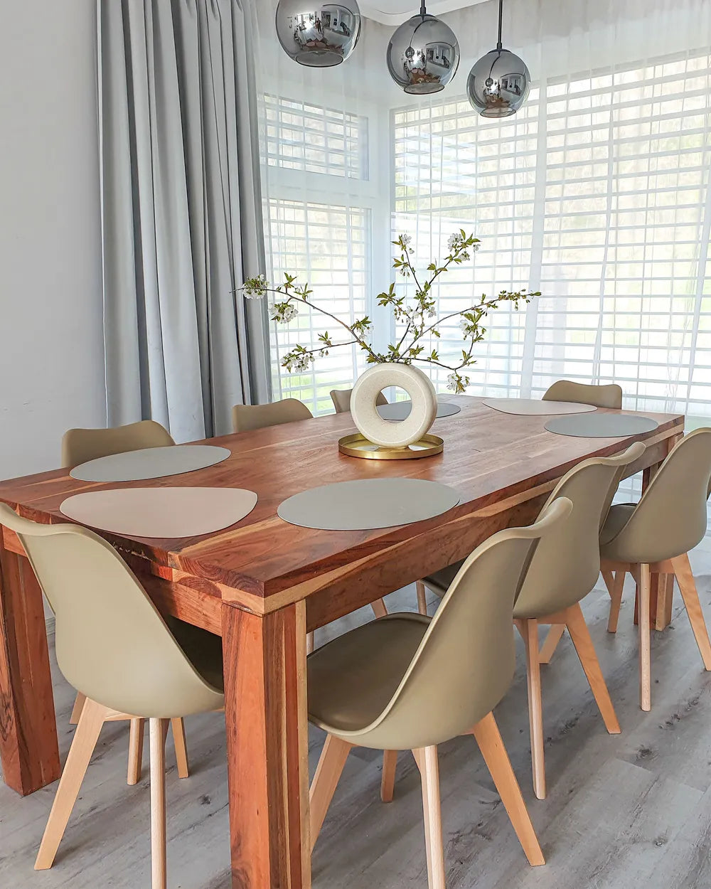 Dining room with wooden table and beige chairs, large windows, and decorative elements.