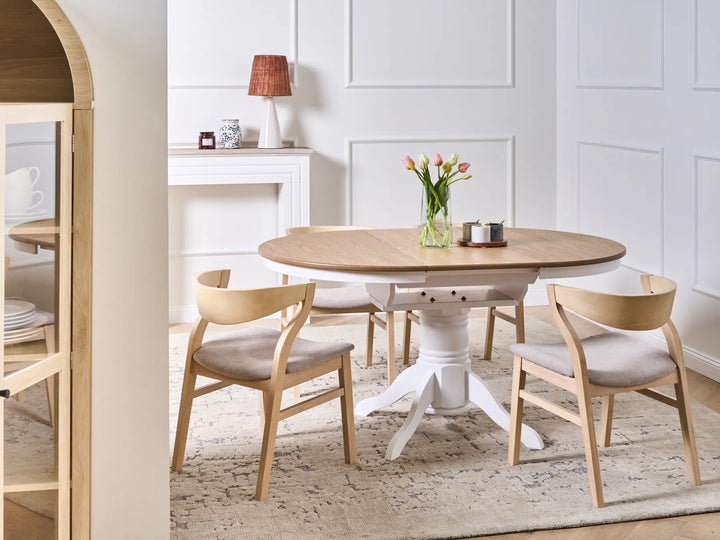Dining room with a round wooden table and chairs in a well-lit room.