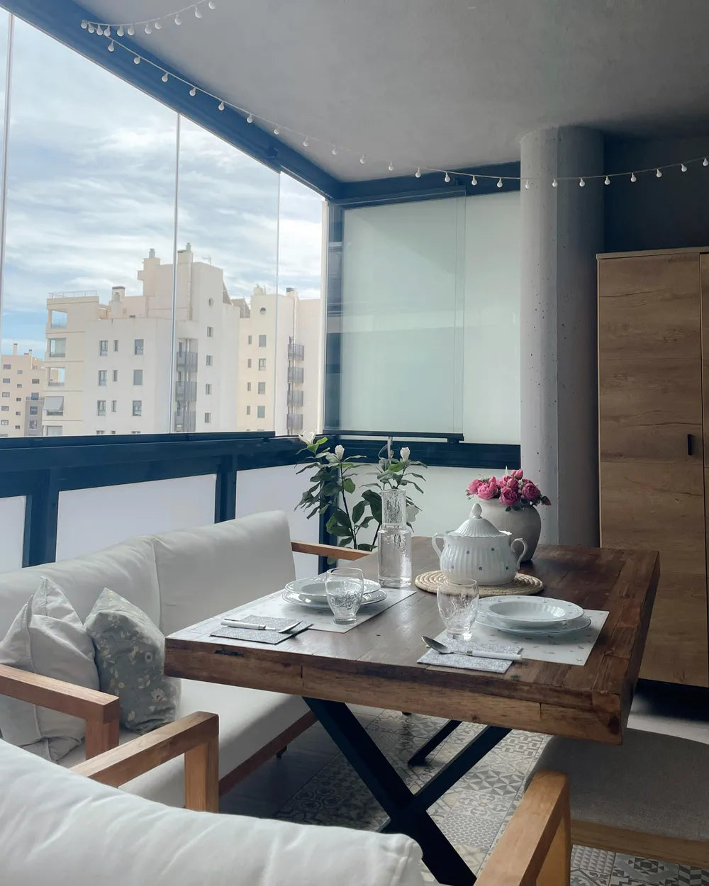 Modern living room with a wooden dining table set and cityscape view.