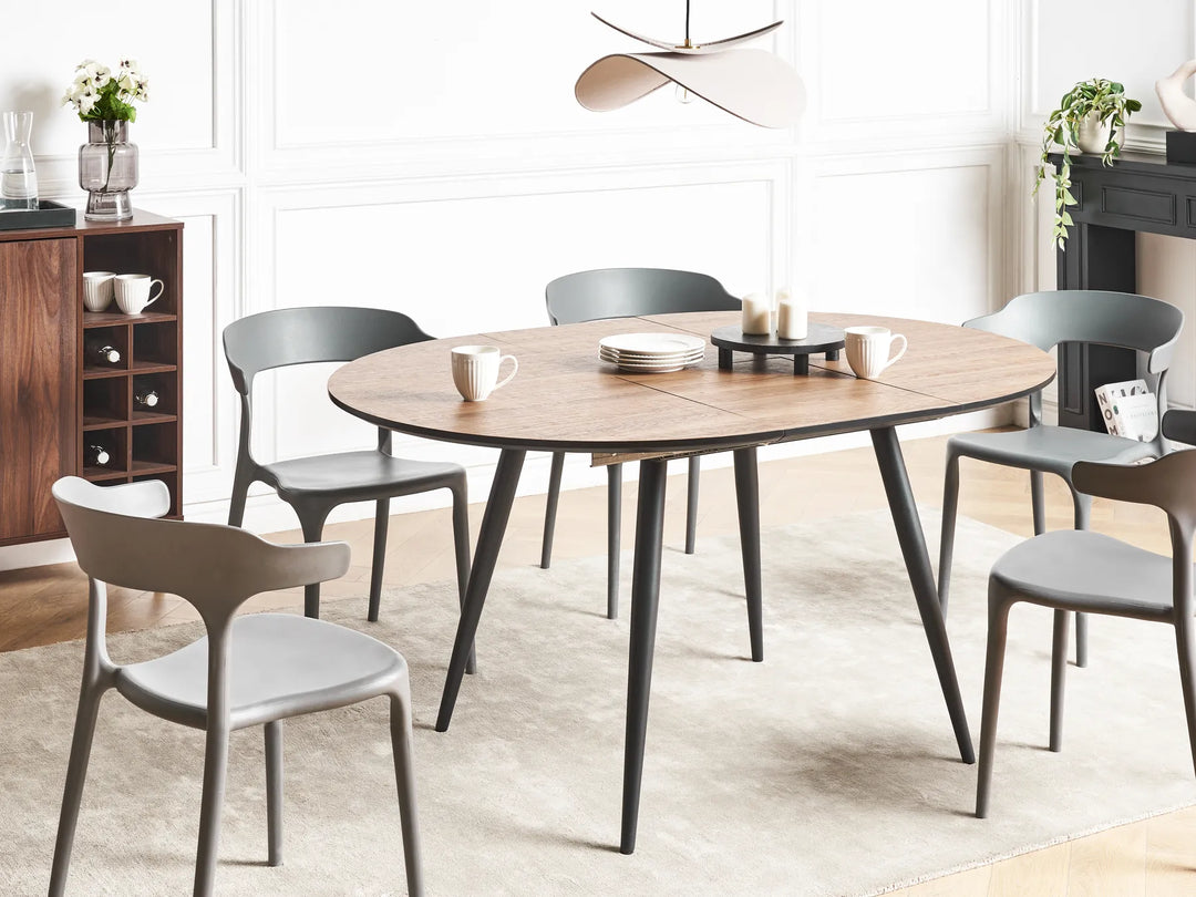Dining room with a round wooden table and gray chairs in a well-lit room.