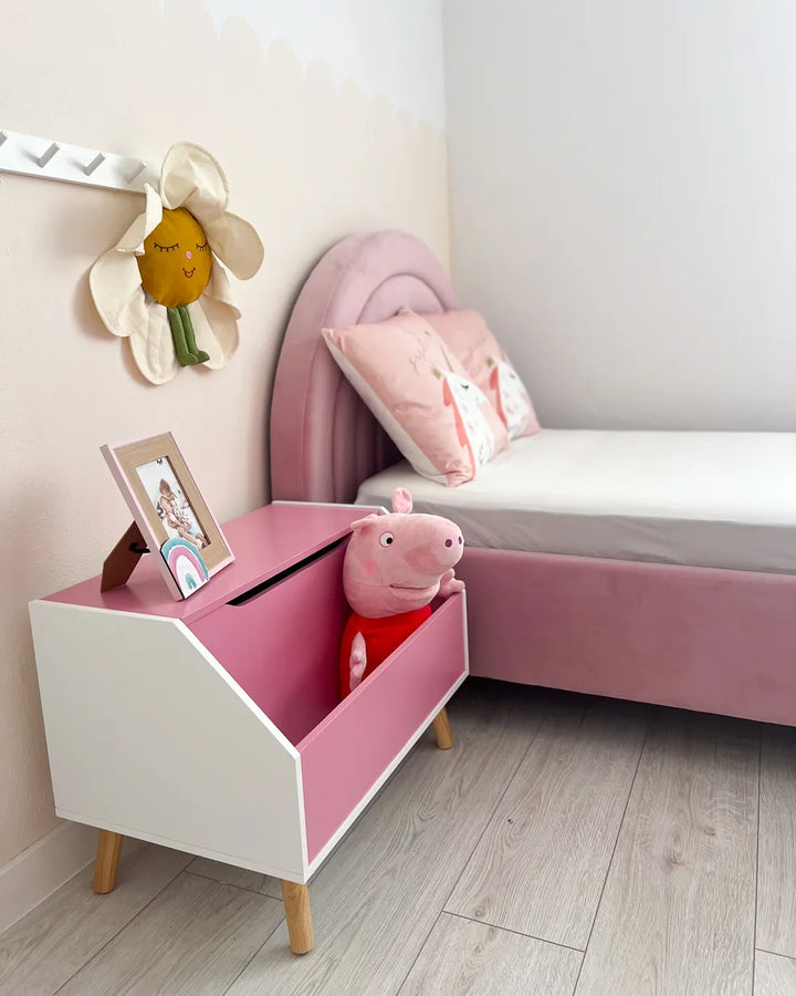 Children's room with pink toy box, bed, and decorative items.