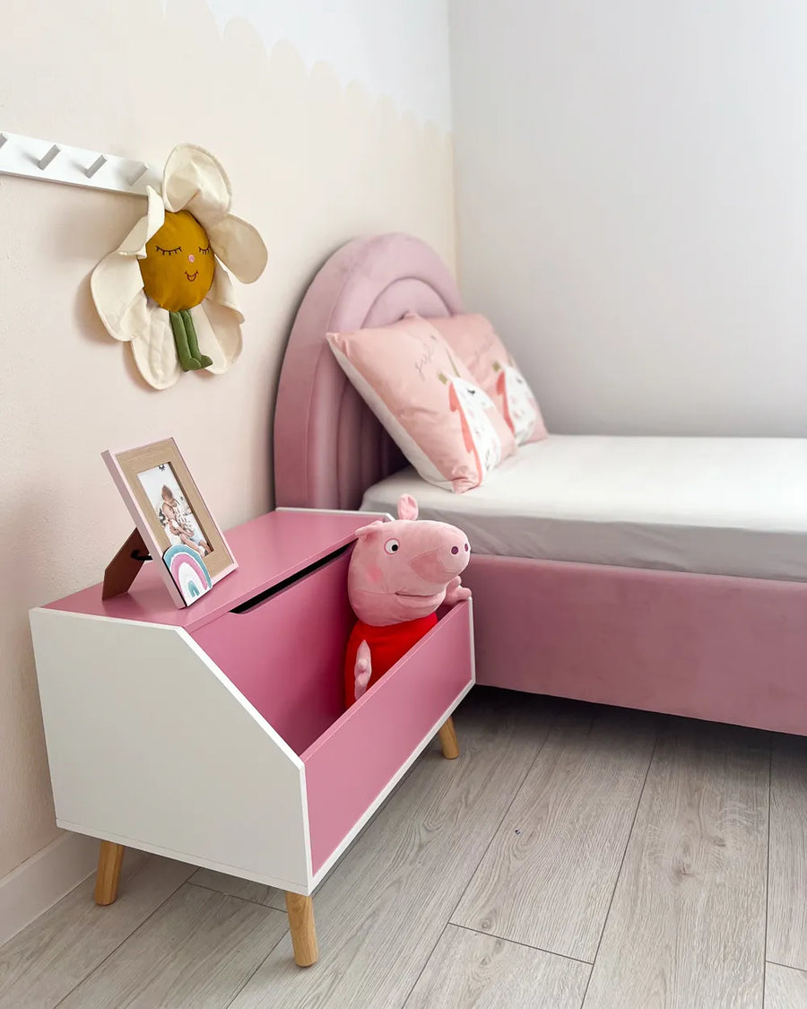 Children's room with pink toy box, bed, and decorative items.