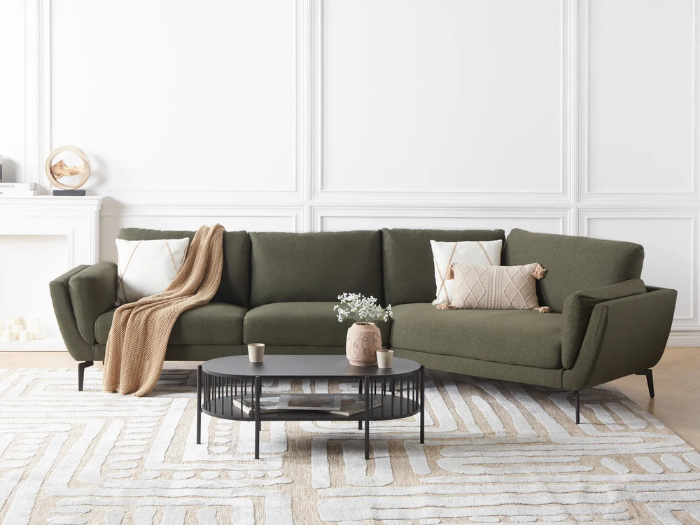 Green sectional sofa in a living room with a coffee table and decorative items.