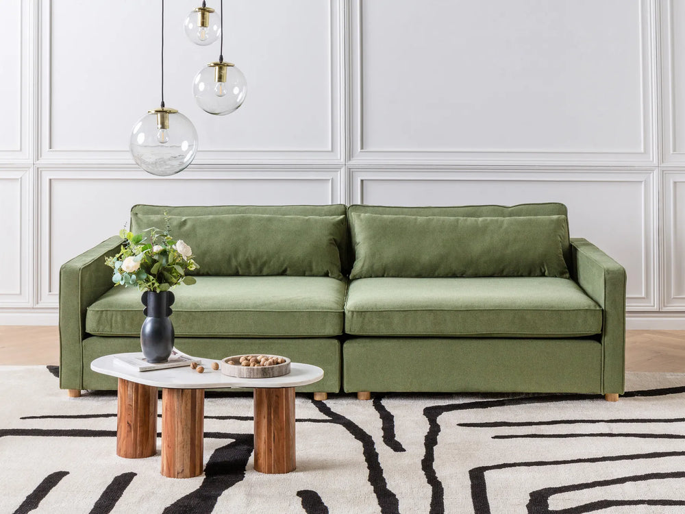 Green sofa in a modern living room with a coffee table and decorative items.