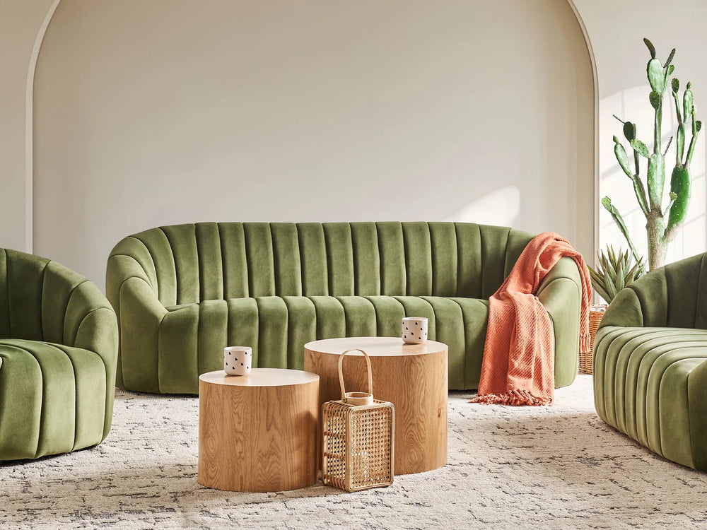 Modern living room with green sofa, wooden tables, and a cactus plant.