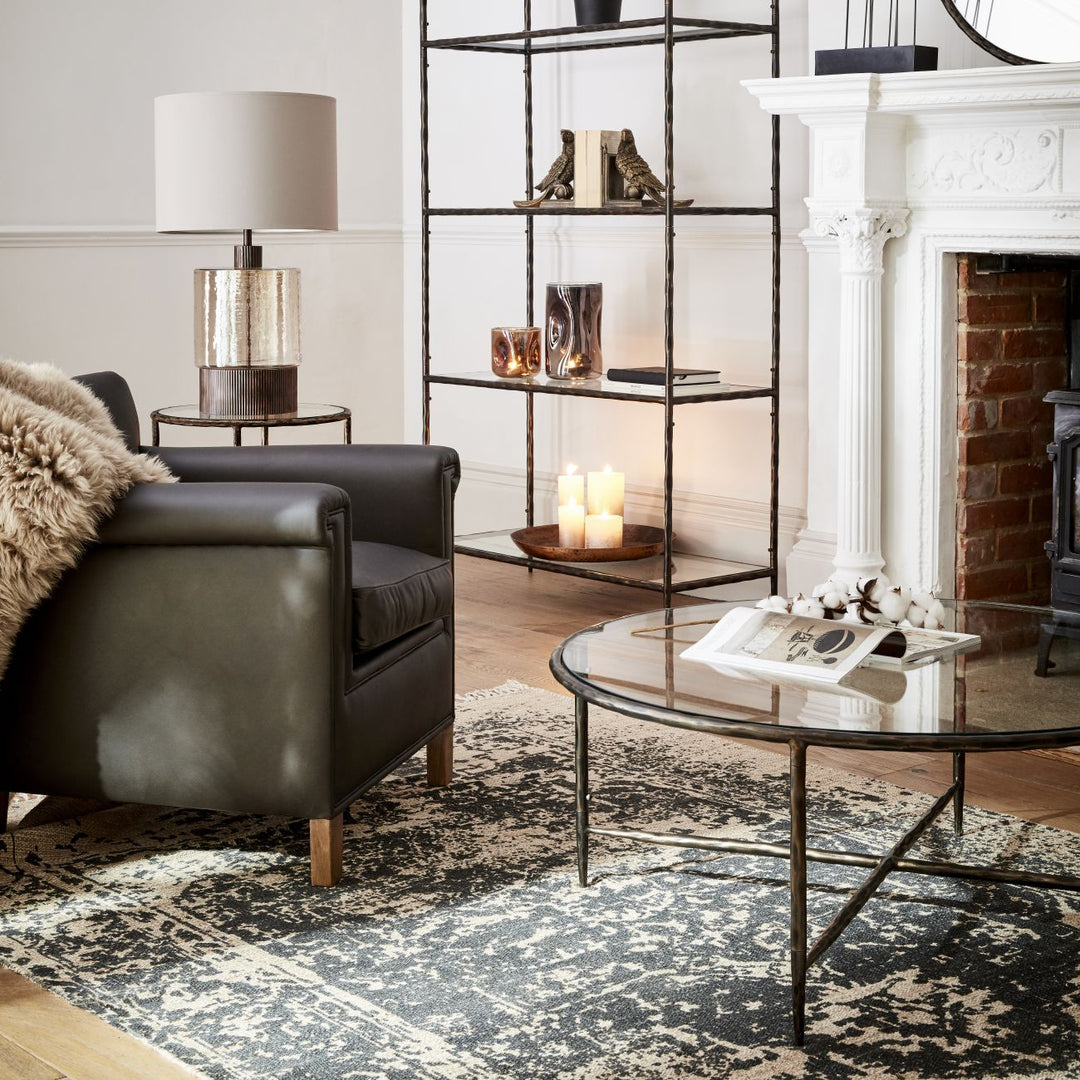 Living room with black leather armchair, glass coffee table, and decorative elements.