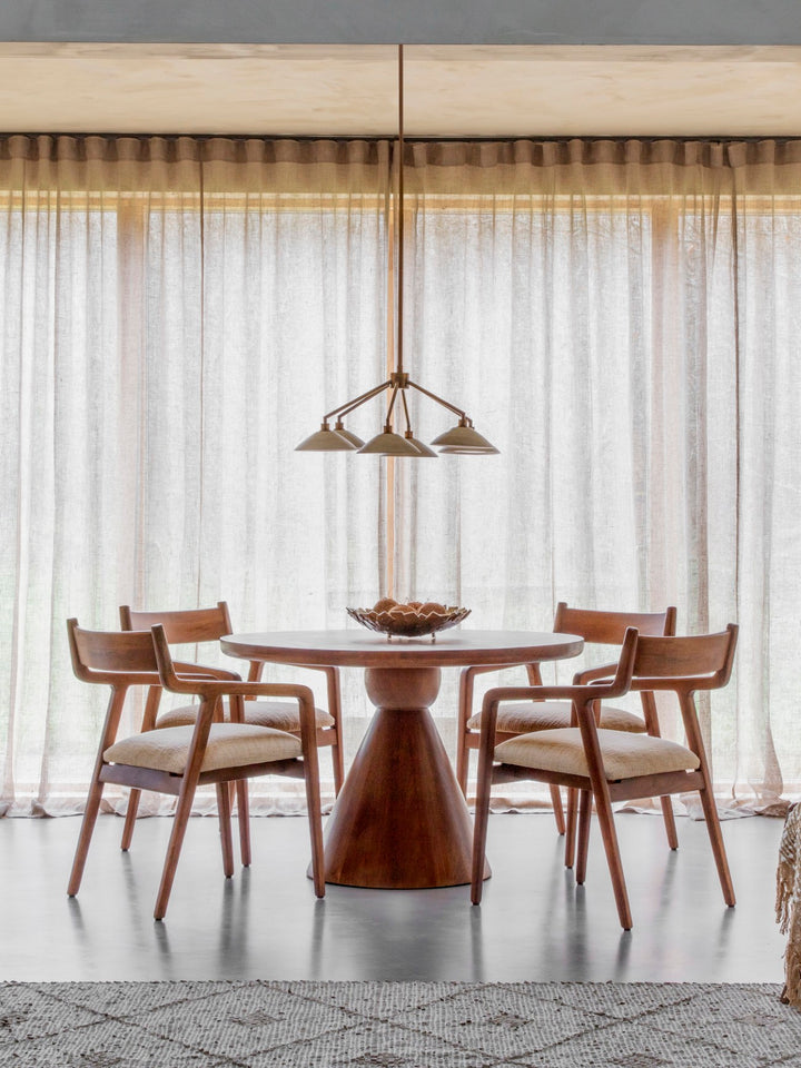 Round dark wood dining table with cone-shaped pedestal in a dining room setting