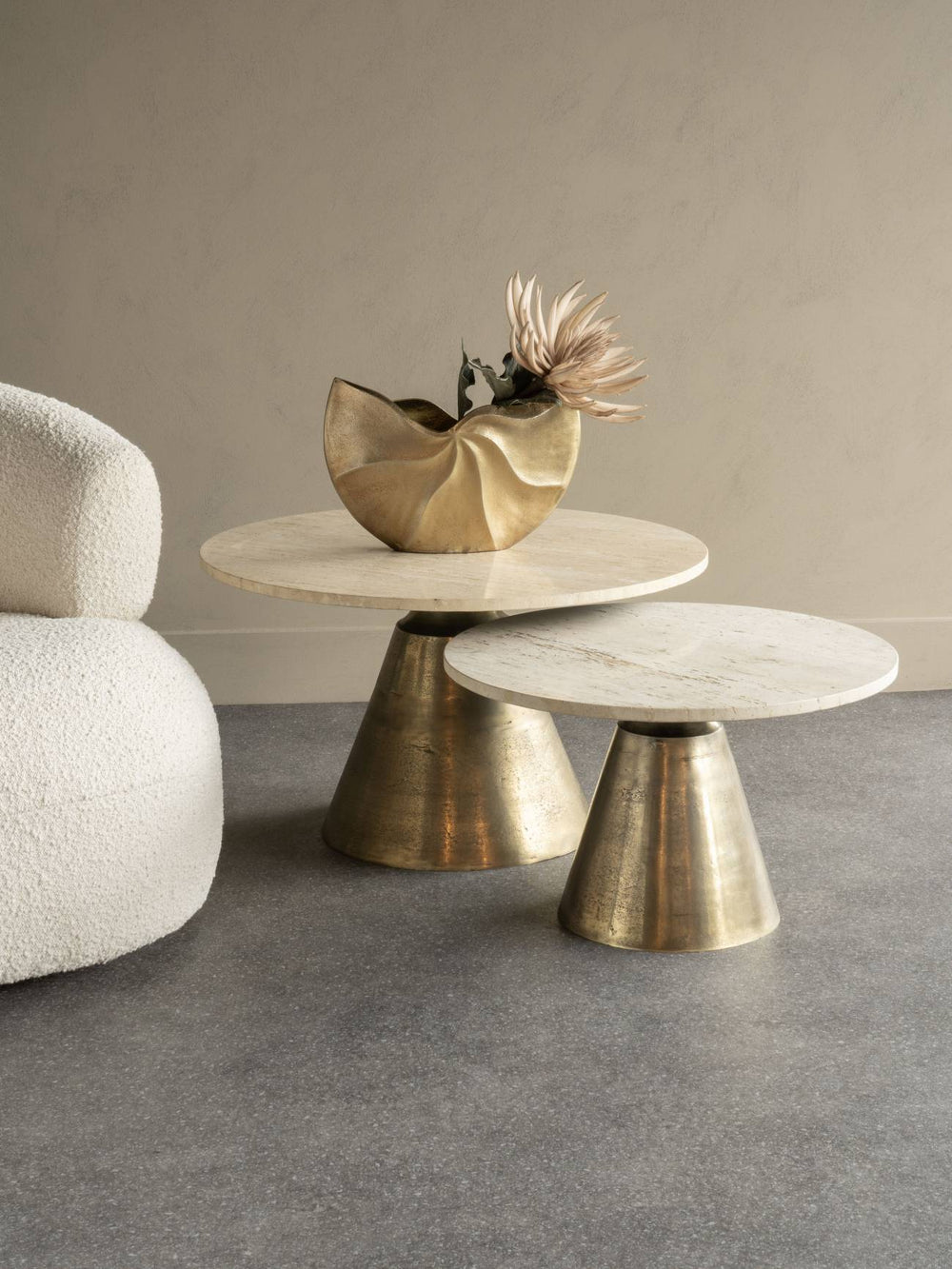 Two marble tables with brass bases in a minimalistic room.