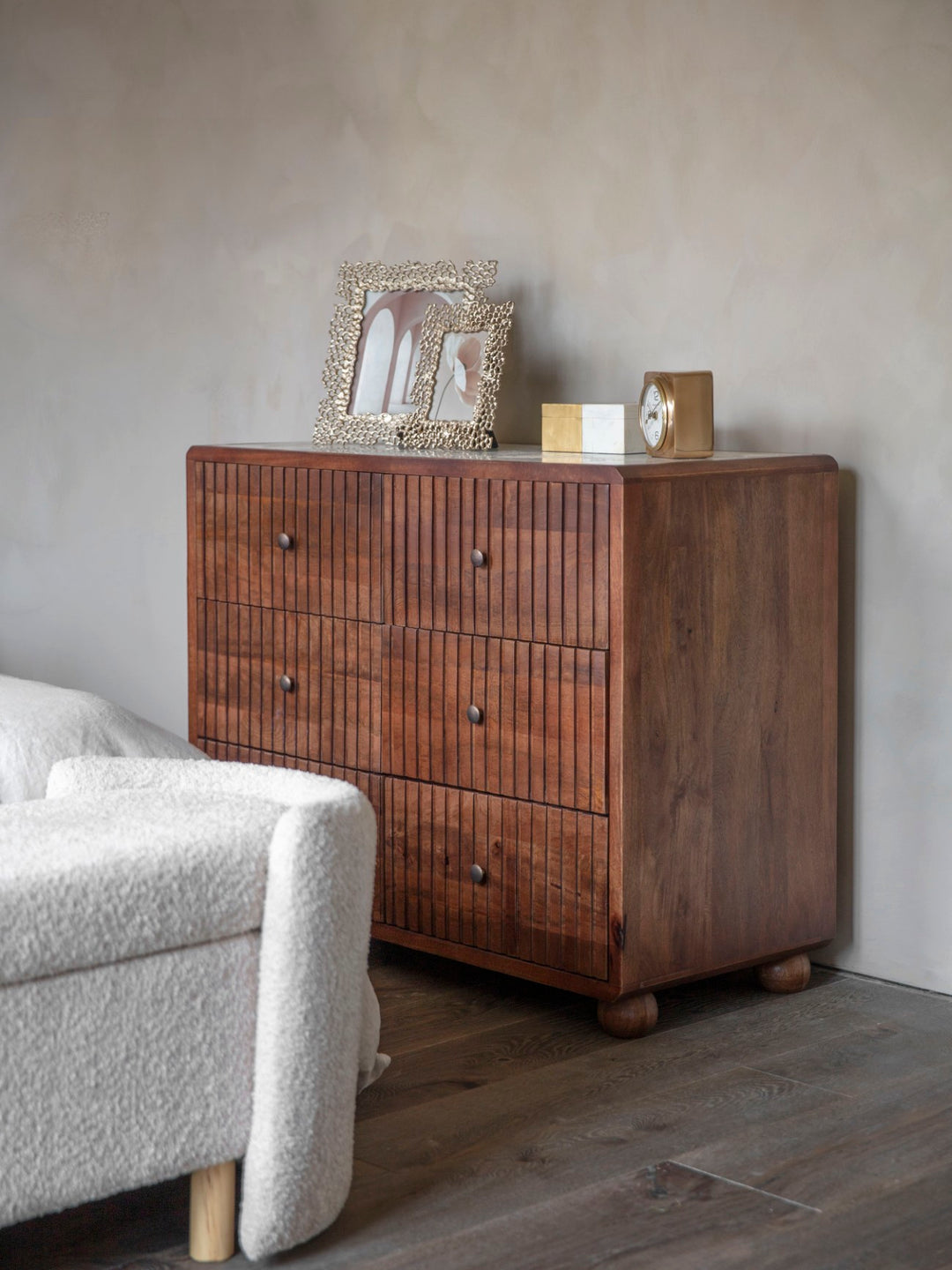 Wooden dresser with decorative items against a gray wall in a room with a sofa.