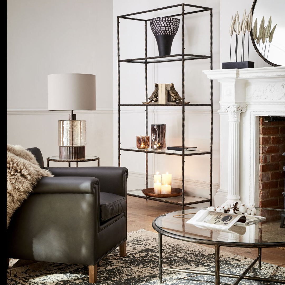 Living room with a black armchair, glass coffee table, and decorative shelves.