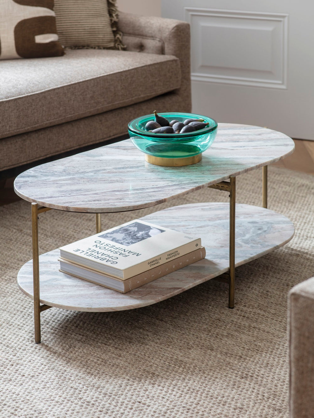 Two-tiered coffee table with books and a bowl on a living room floor.