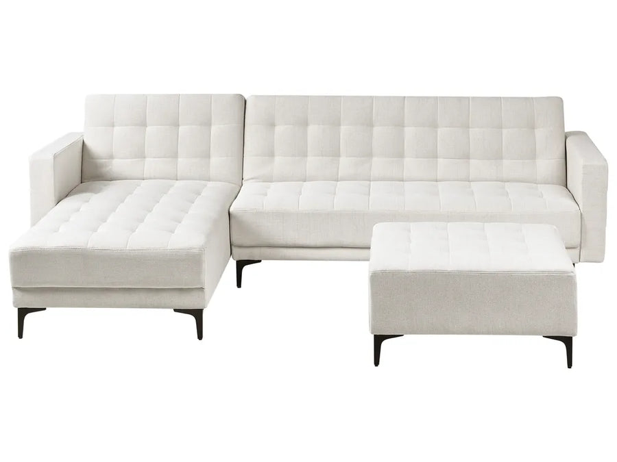 White tufted sectional sofa with ottoman on a white background