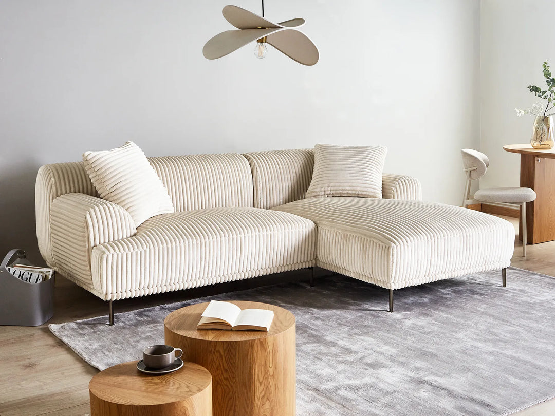 Beige sectional sofa in a modern living room with wooden coffee table and decorative items.