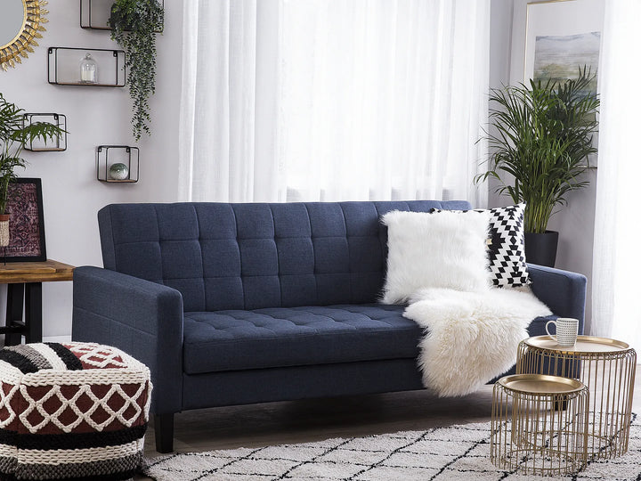 Blue tufted sofa with decorative pillows in a living room setting.