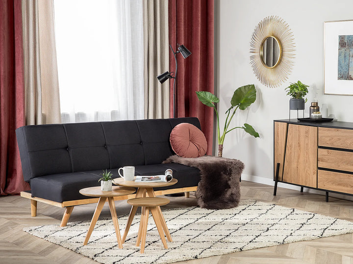 Modern living room with black sofa, wooden coffee table, and decorative elements.