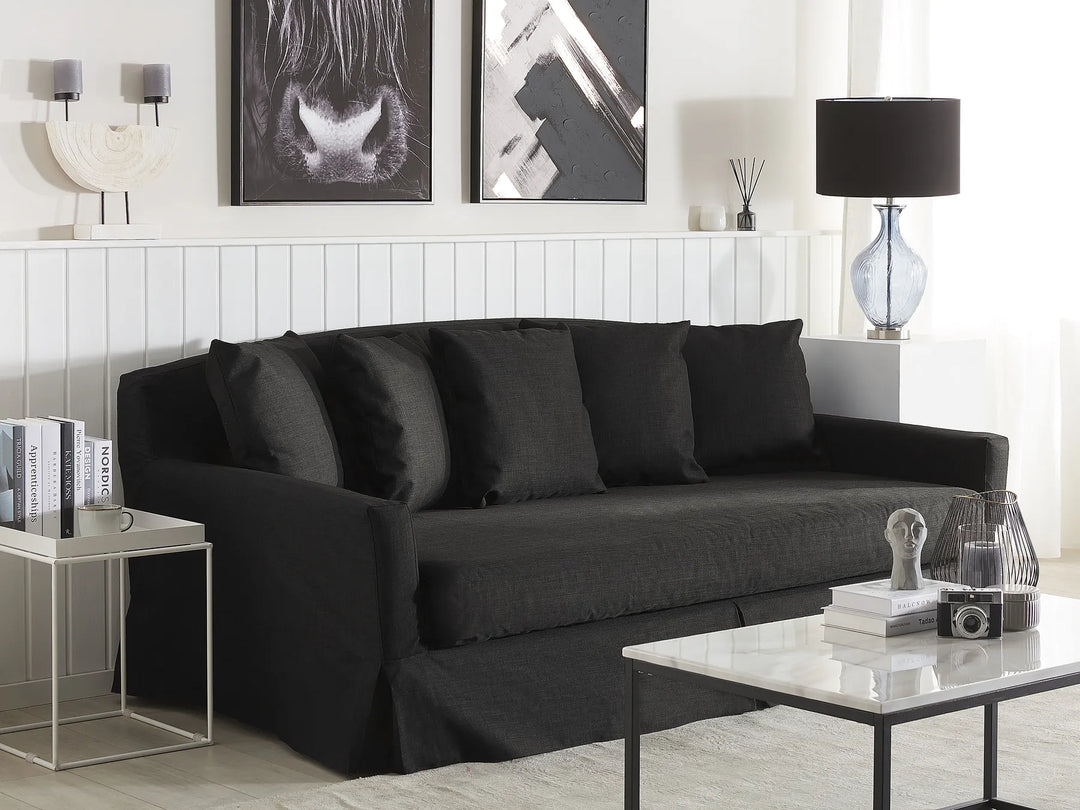 Modern living room with a black sofa, coffee table, and decorative items.