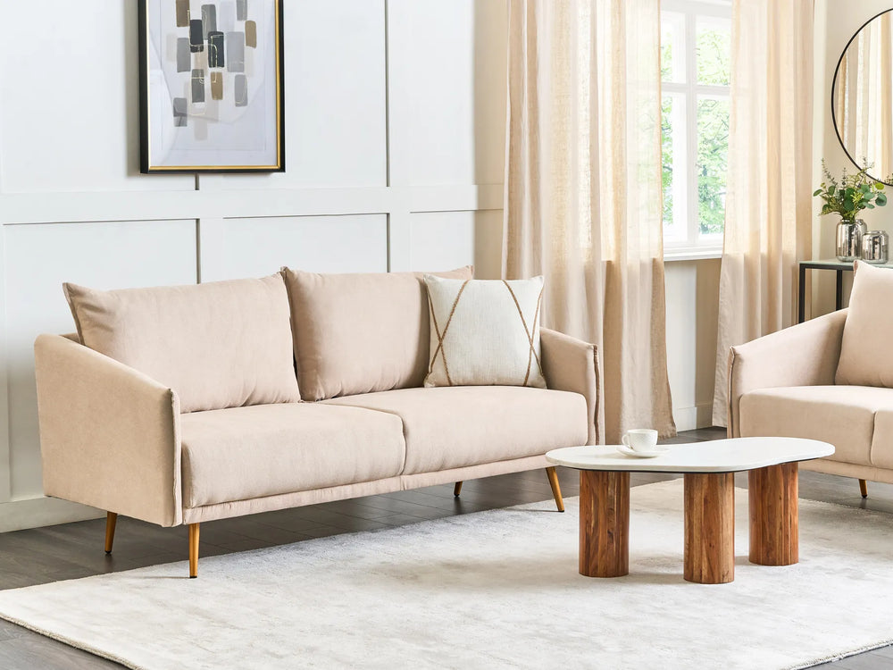 Beige sofa in a living room with a coffee table and decorative elements.