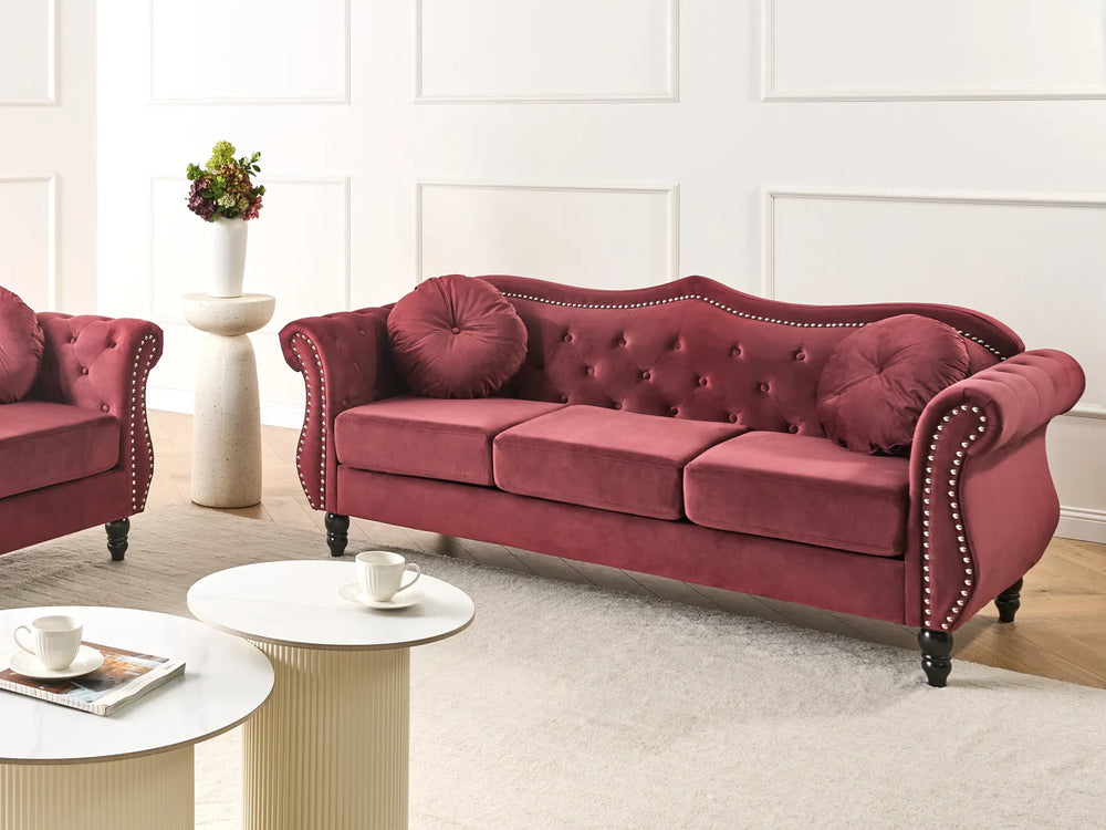 Red velvet sofa in a living room setting with a white wall and light-colored floor.