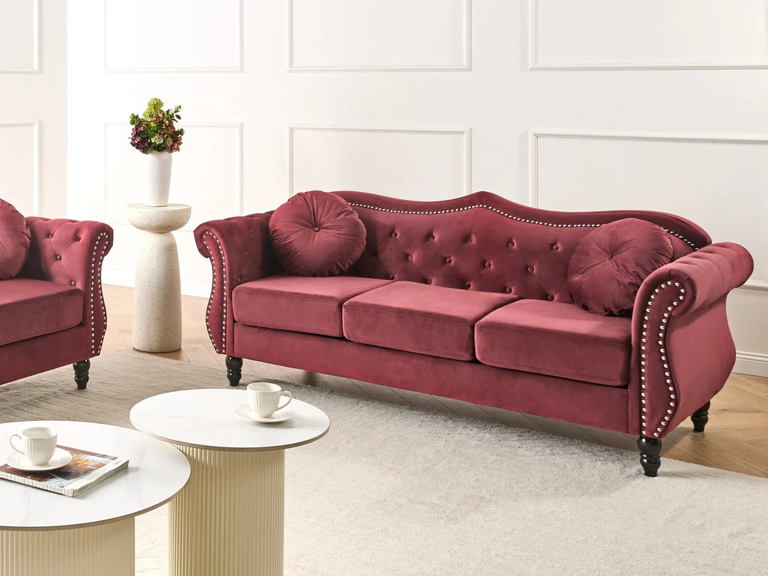 Red velvet sofa in a living room setting with a white wall and light-colored floor.