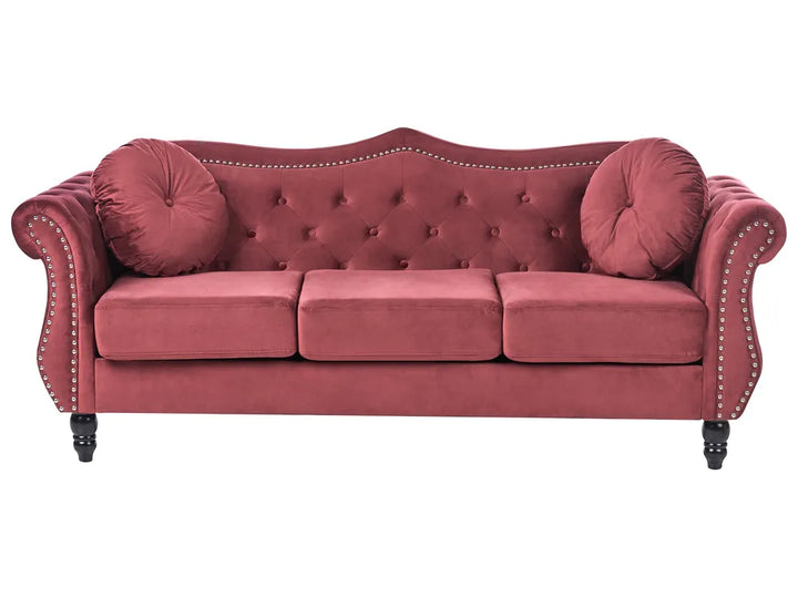 Red velvet sofa with buttoned backrest and nailhead trim on a white background