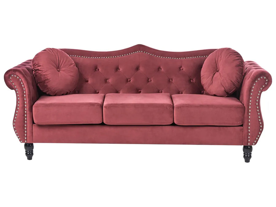 Red velvet sofa with buttoned backrest and nailhead trim on a white background