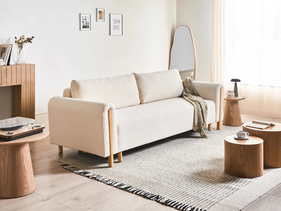 Beige sofa in a modern living room with wooden tables and decor.