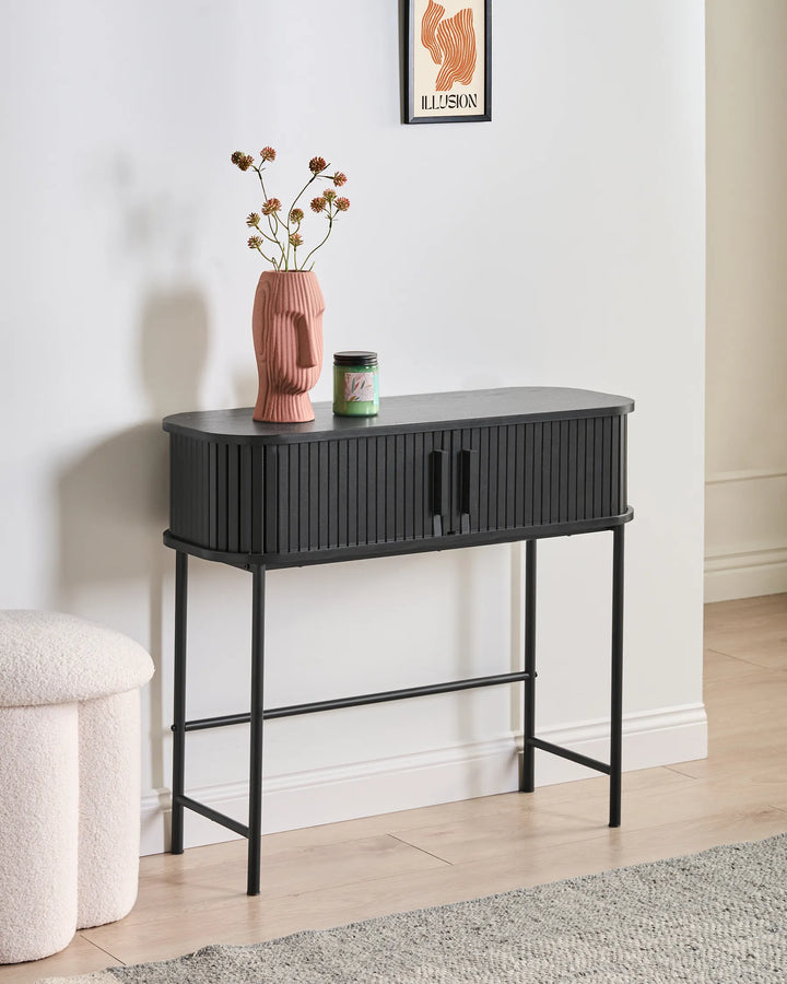 Black console table with decorative items against a white wall