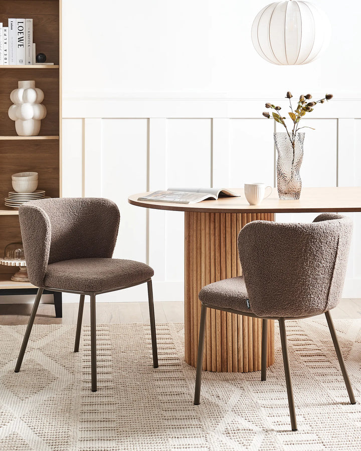 Dining room with two brown chairs around a wooden table, bookshelf in the background.
