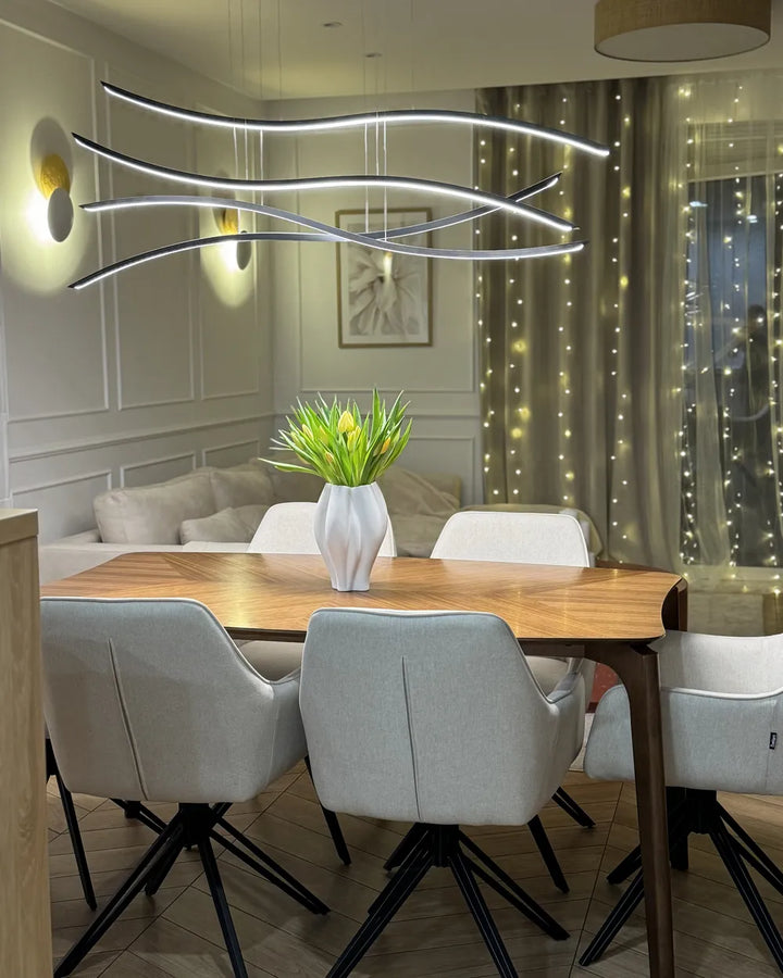 Modern dining room with a stylish chandelier, wooden table, and gray chairs.