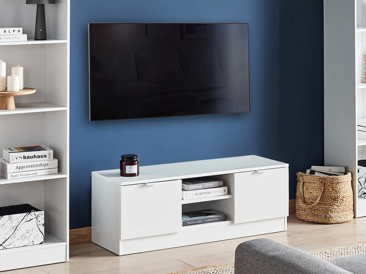 White TV stand with a television mounted on a blue wall in a room with shelves and decor.