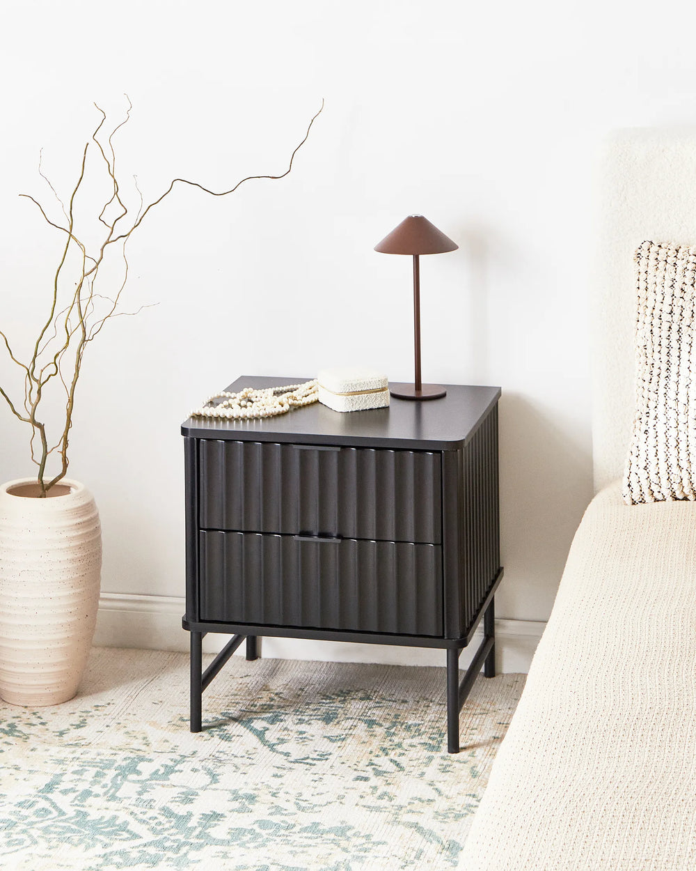 Black metal nightstand with decorative items in a bedroom setting