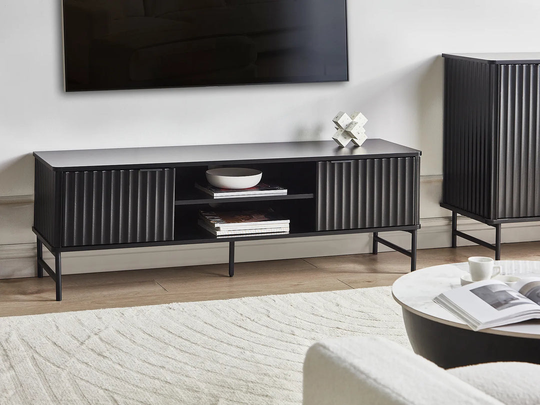 Modern living room with a black entertainment console, TV, and decor items.