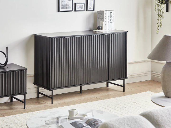 Modern black sideboard in a living room setting with decor items on top.
