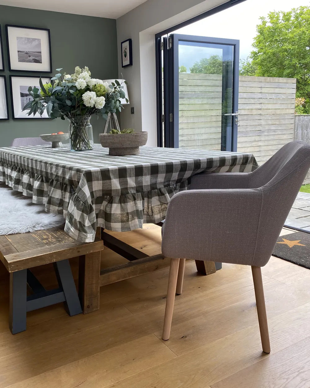 Dining room with a checkered tablecloth, gray chairs, and a view of a garden.