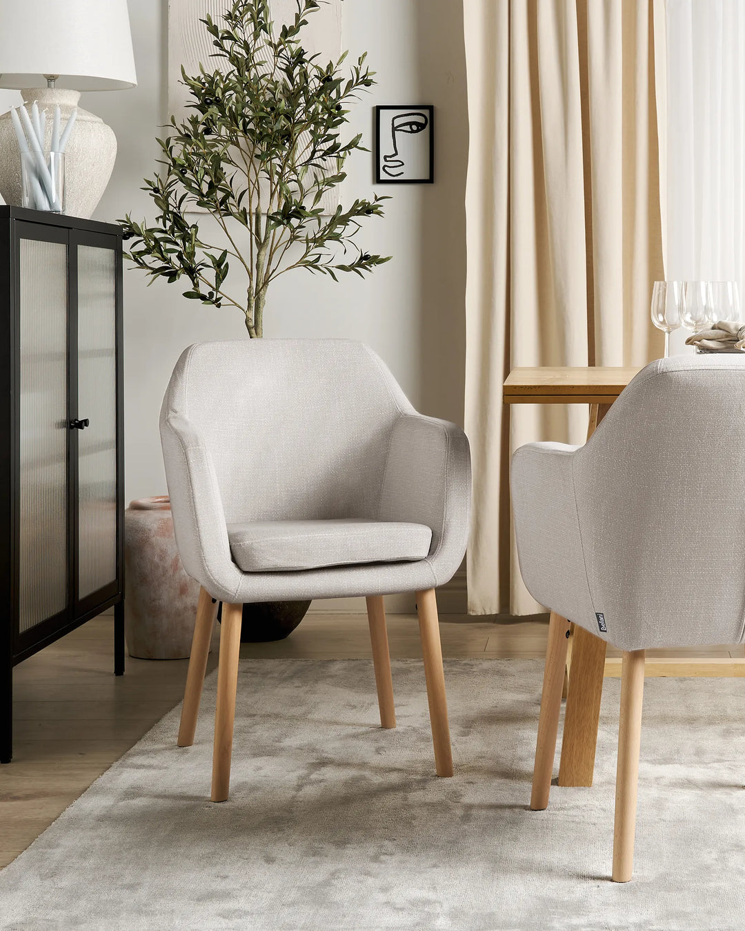 Gray chairs with wooden legs in a room with a plant and table.