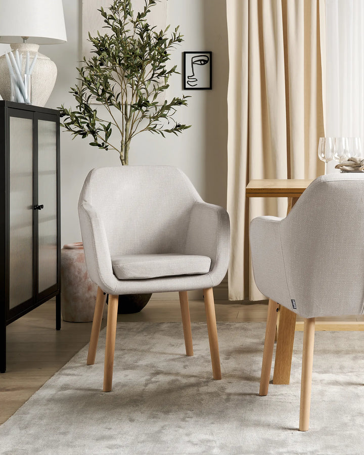 Gray chairs with wooden legs in a room with a plant and table.