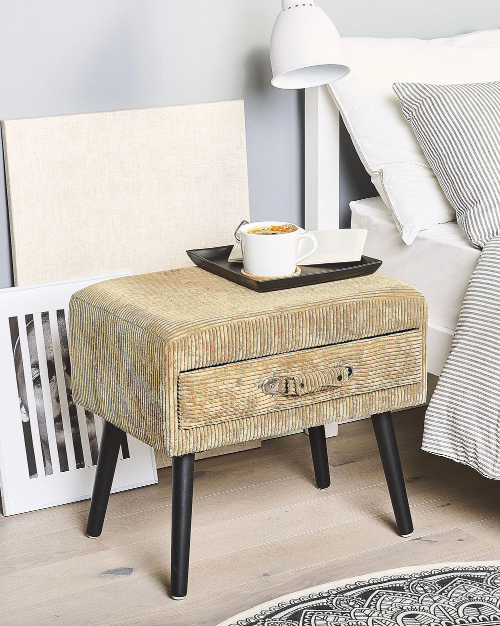 Beige textured nightstand with a drawer next to a bed with striped bedding.