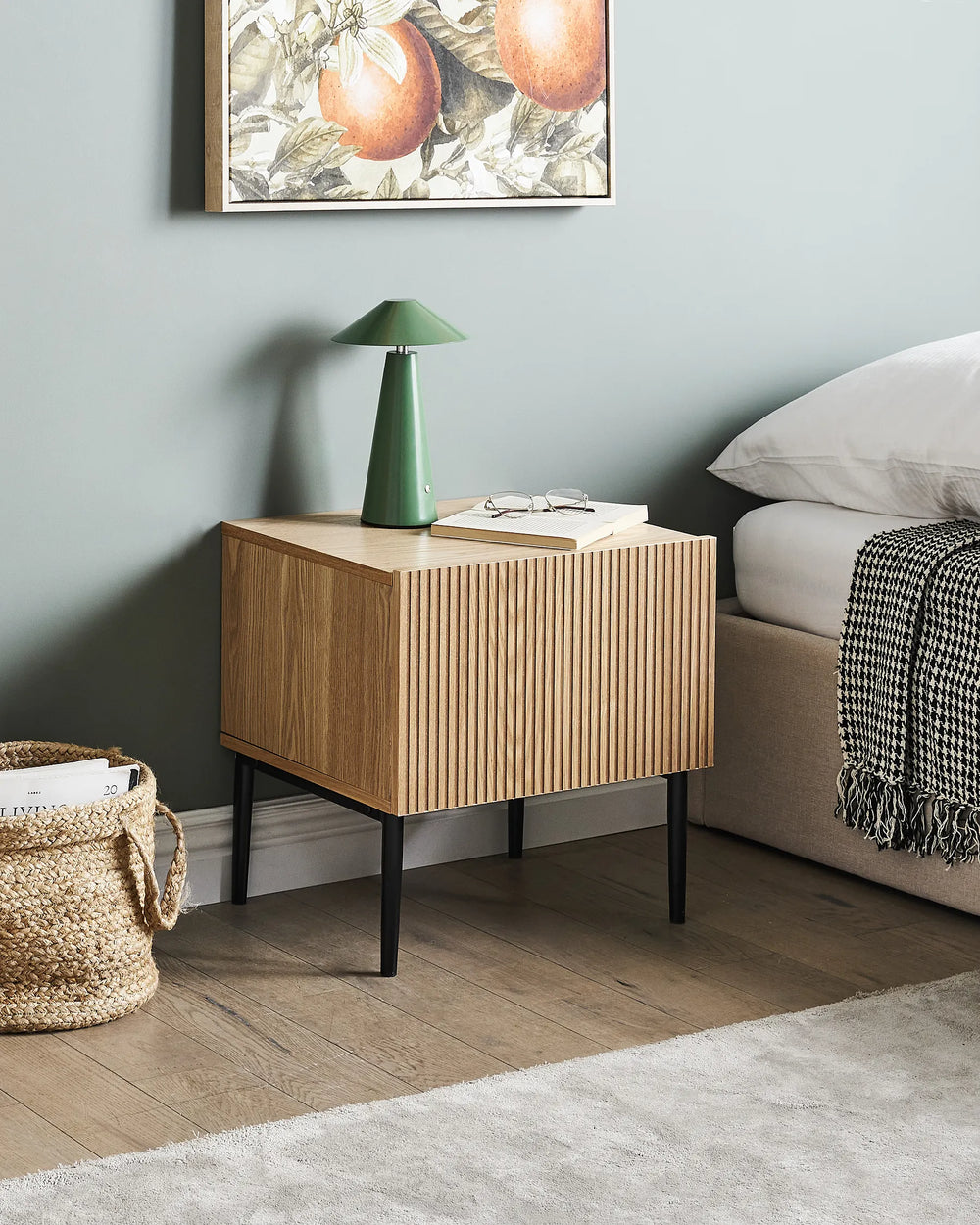Wooden nightstand with a green lamp in a bedroom setting