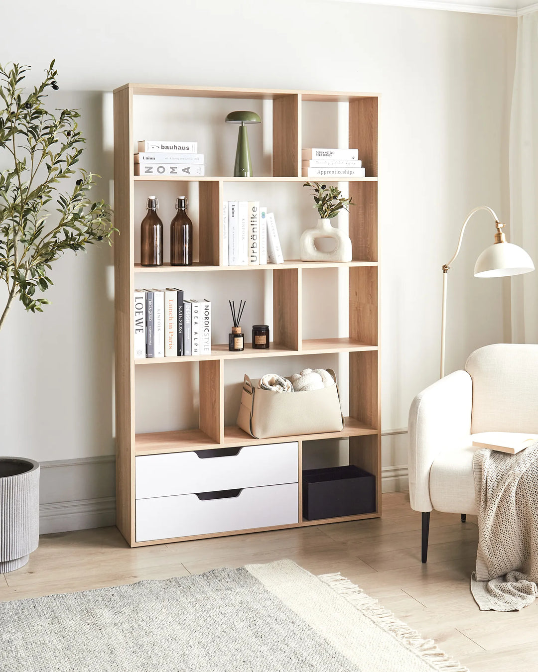 Wooden bookshelf with books and decor items in a room with a chair and lamp.