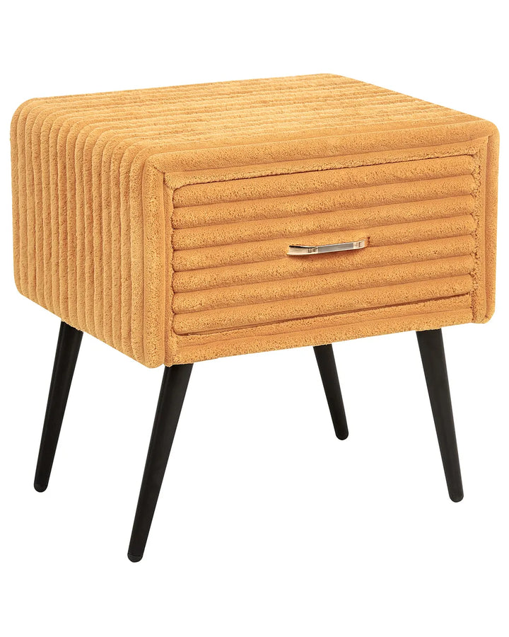 A modern mustard yellow ribbed velvet side table with black tapered legs and a silver metal pull handle, shown on a plain white background.